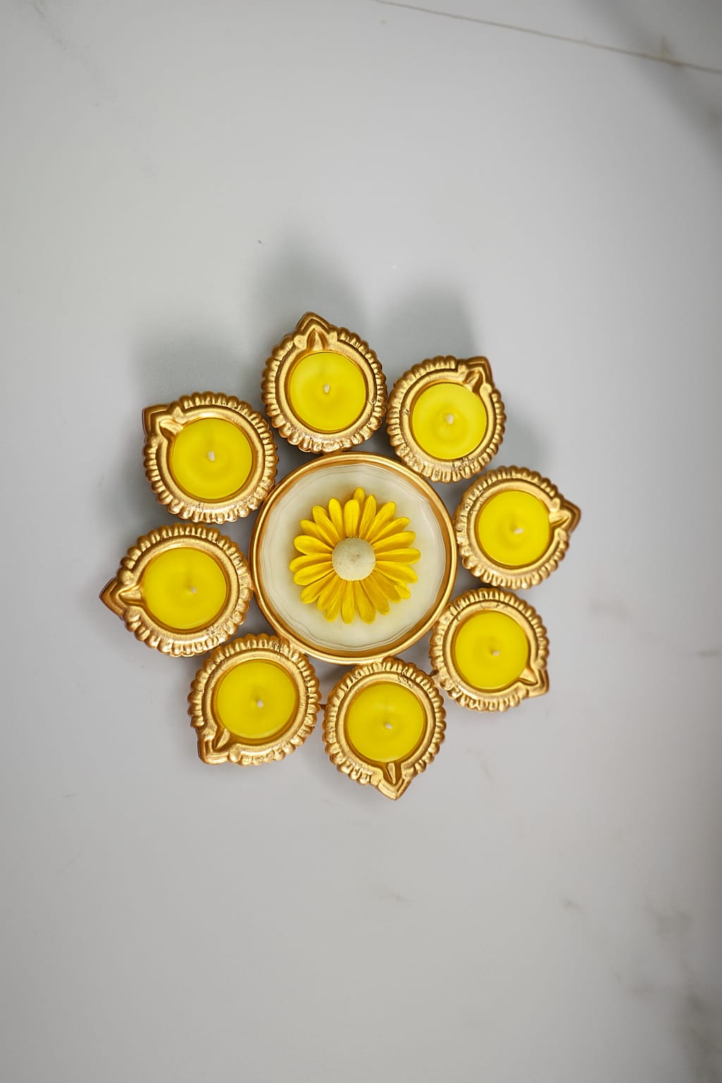 Decorative Urli candle with yellow candles and gold accents on a white background